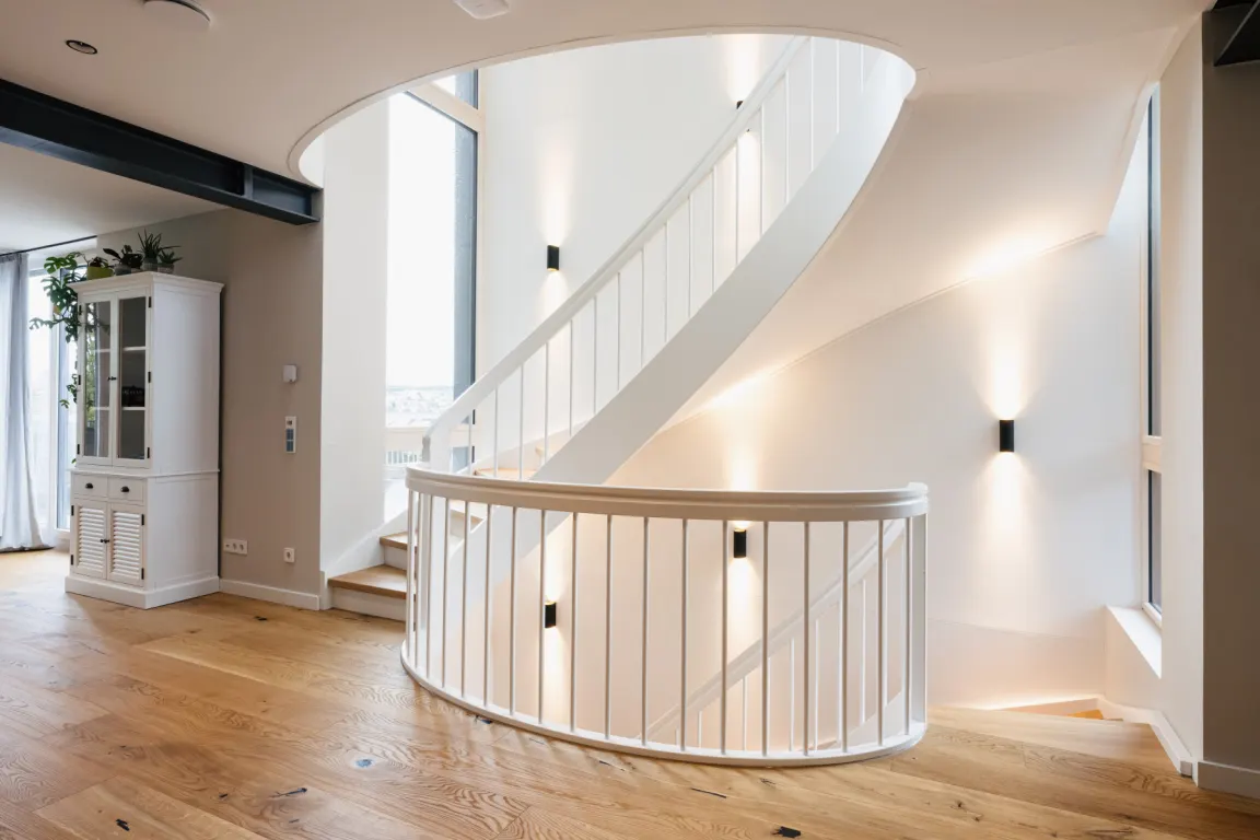 Fertig montierte weiße Wendeltreppe mit Holzstufen in einem hellen Wohnraum